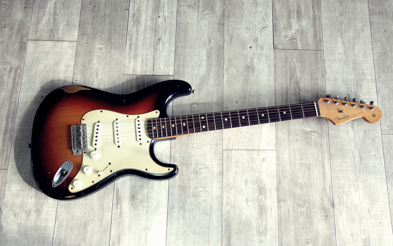 Электрогитара лежит на деревянном полу