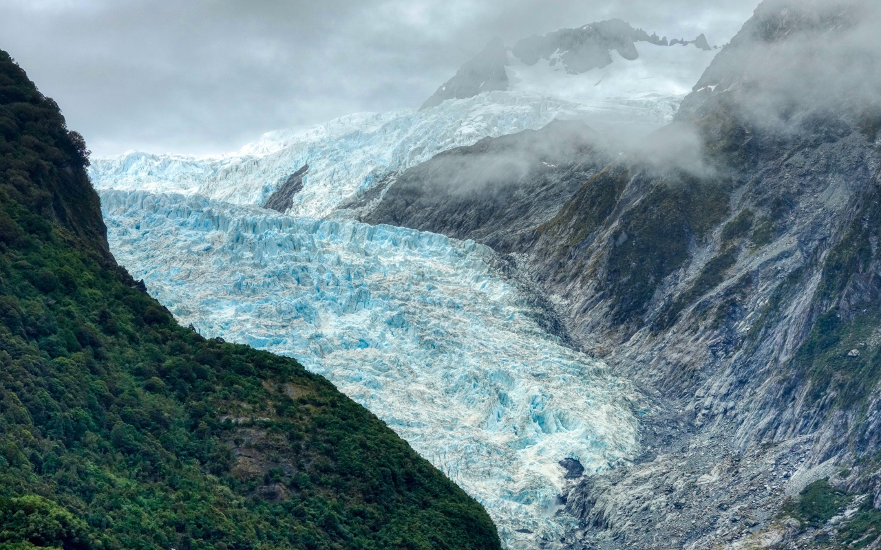 Голубой ледник между скал под грозовым небом