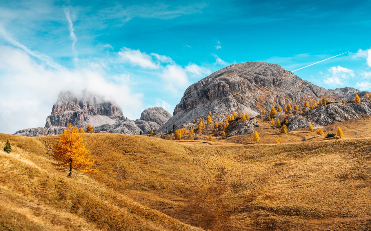 Холмы с сухой травой у гор под голубым небом