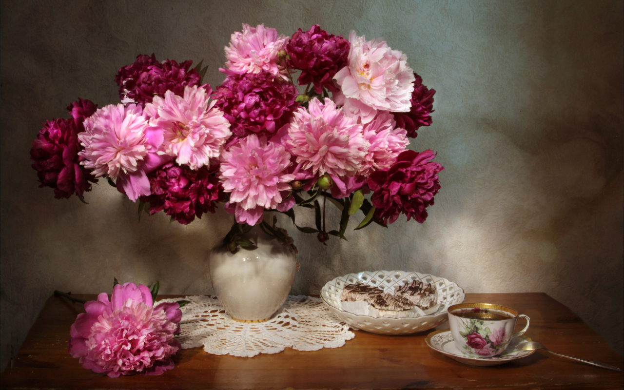 Большой букет розовых пионов в вазе на столе 