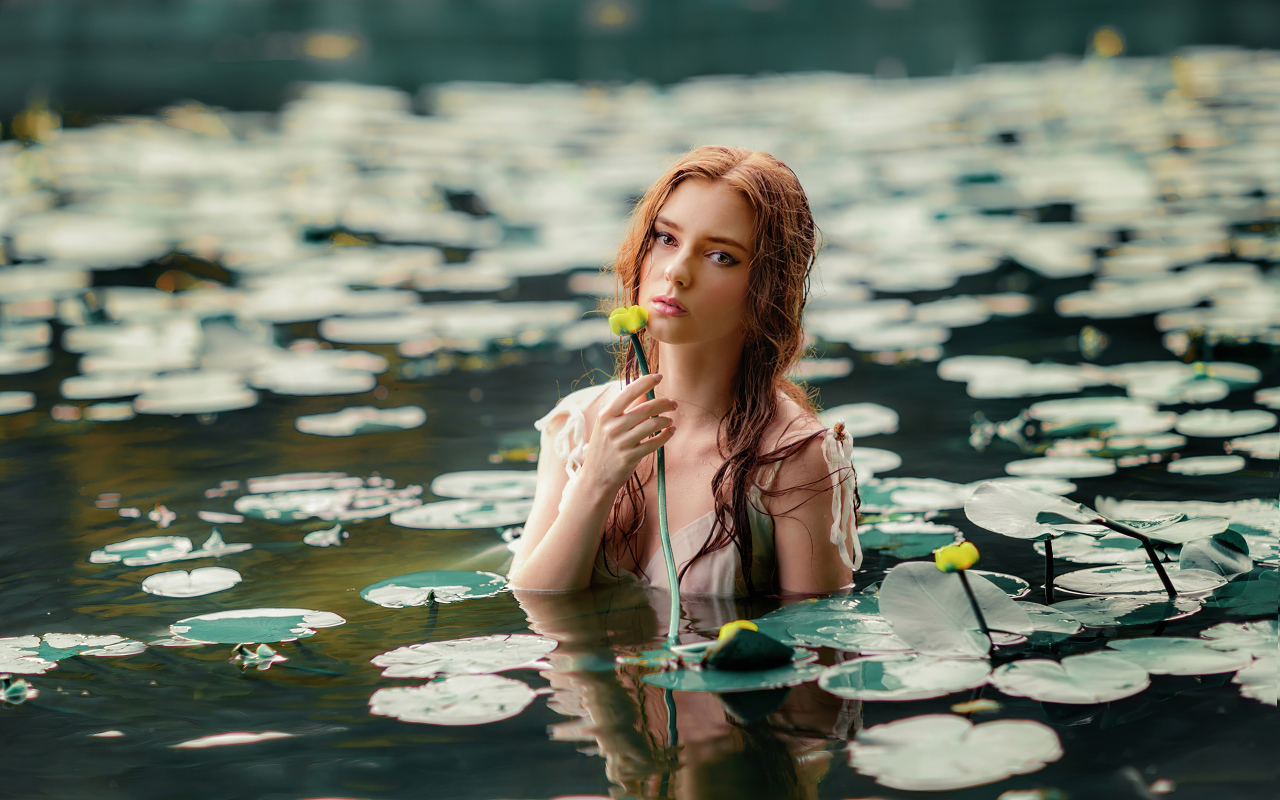 Красивая молодая девушка с водяными лилиями в пруду