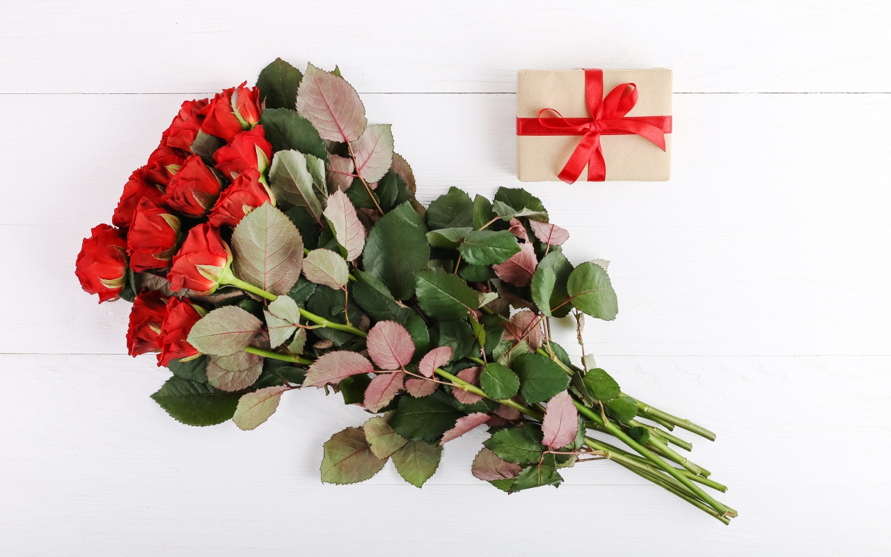 Букет колючих красных роз с подарком на белом фоне