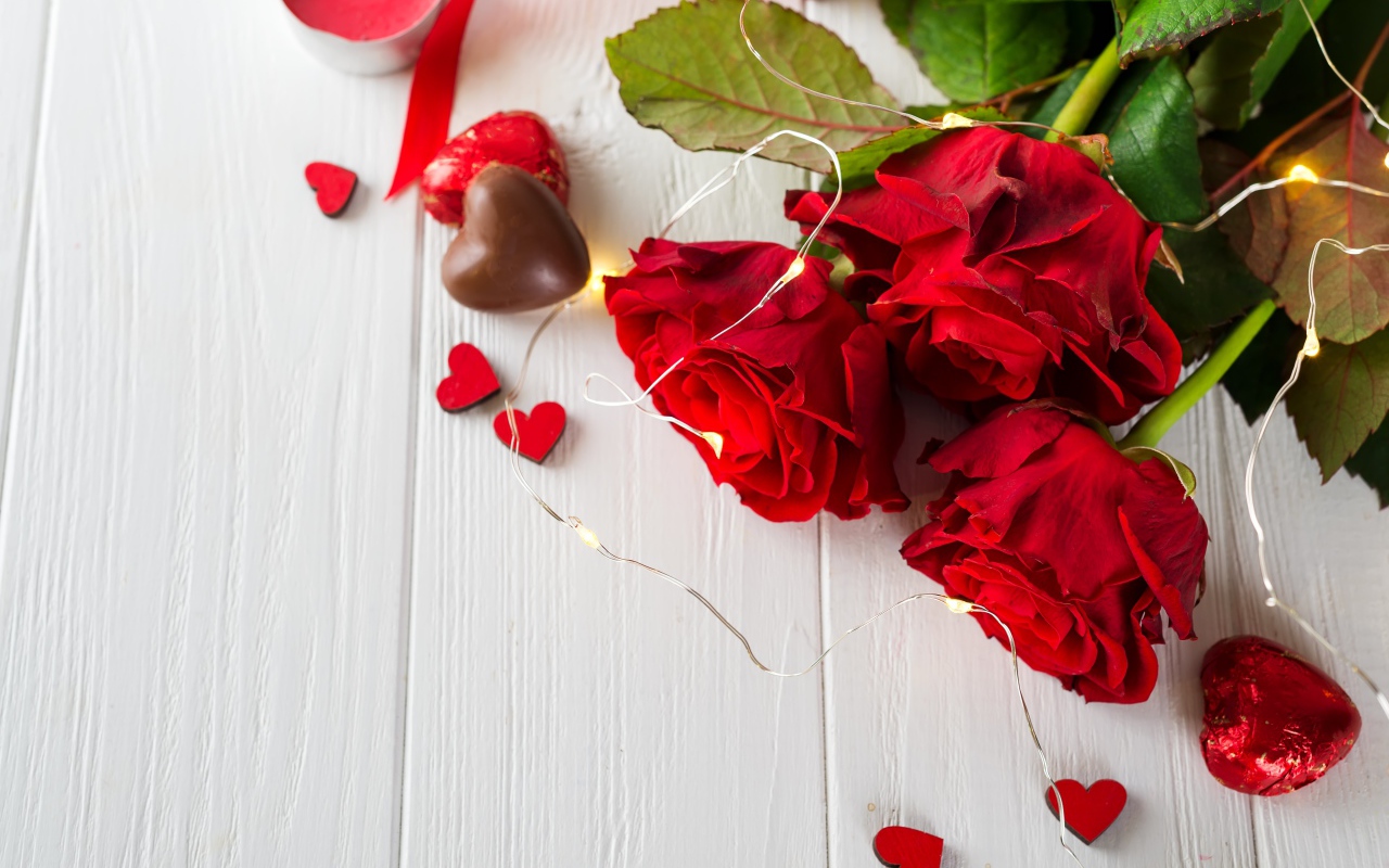 Букет красных роз с конфетами на столе