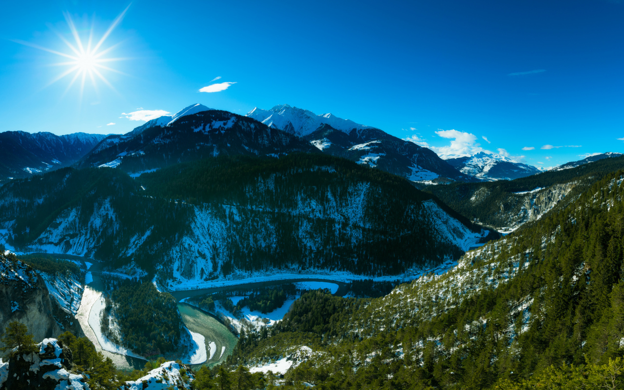 Яркое солнце в голубом небе над заснеженными горами, Швейцария 