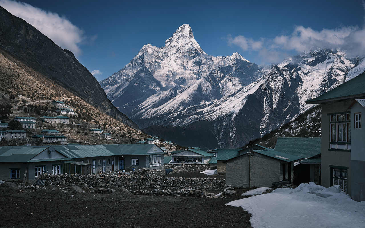 Поселок на фоне заснеженных гор под голубым небом 