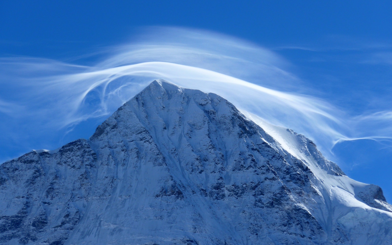 White cloud in blue sky over snowy mountain peak