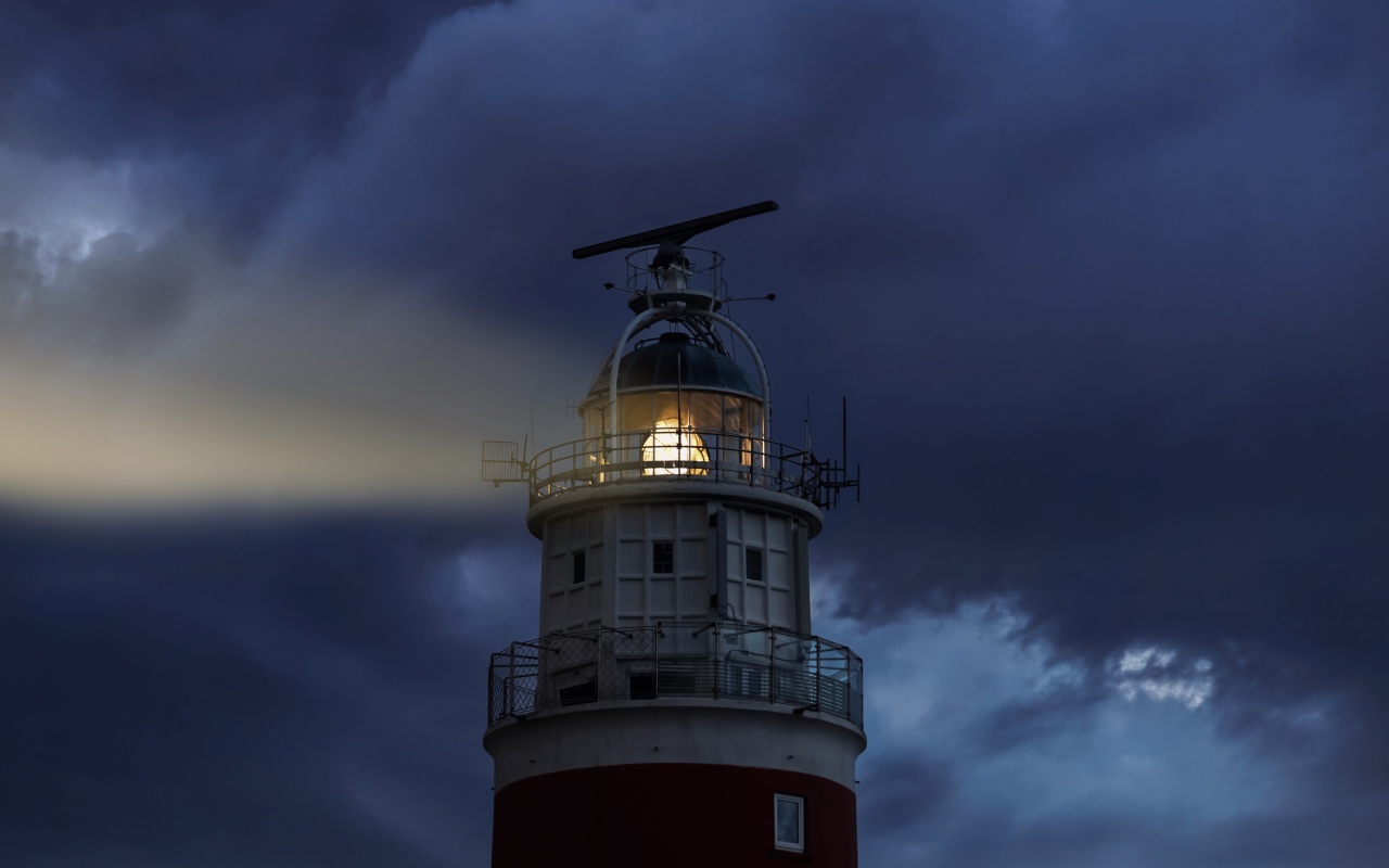 Грозовое небо над включенным маяком ночью
