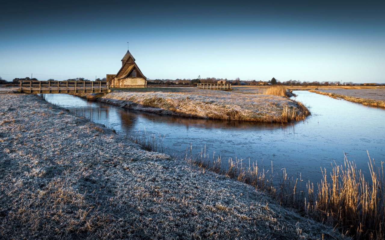 Иней покрывает землю холодным утром у реки