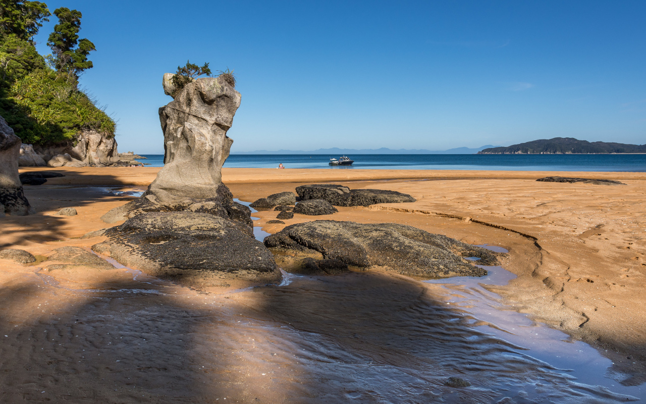 Большие камни на берегу на мокром песке у моря летом 