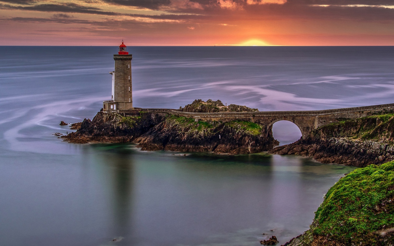 Вид на спокойное море и маяк на закате солнца 