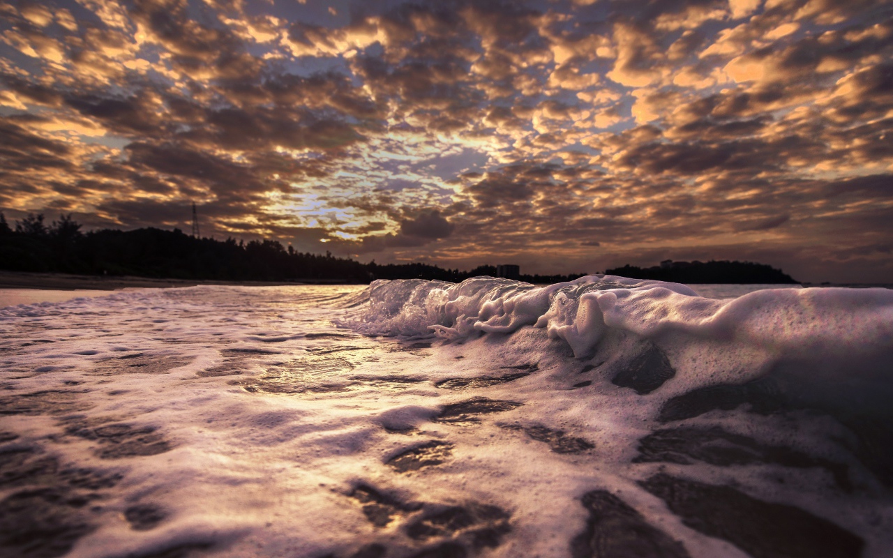 Белые волны на песке на рассвете 