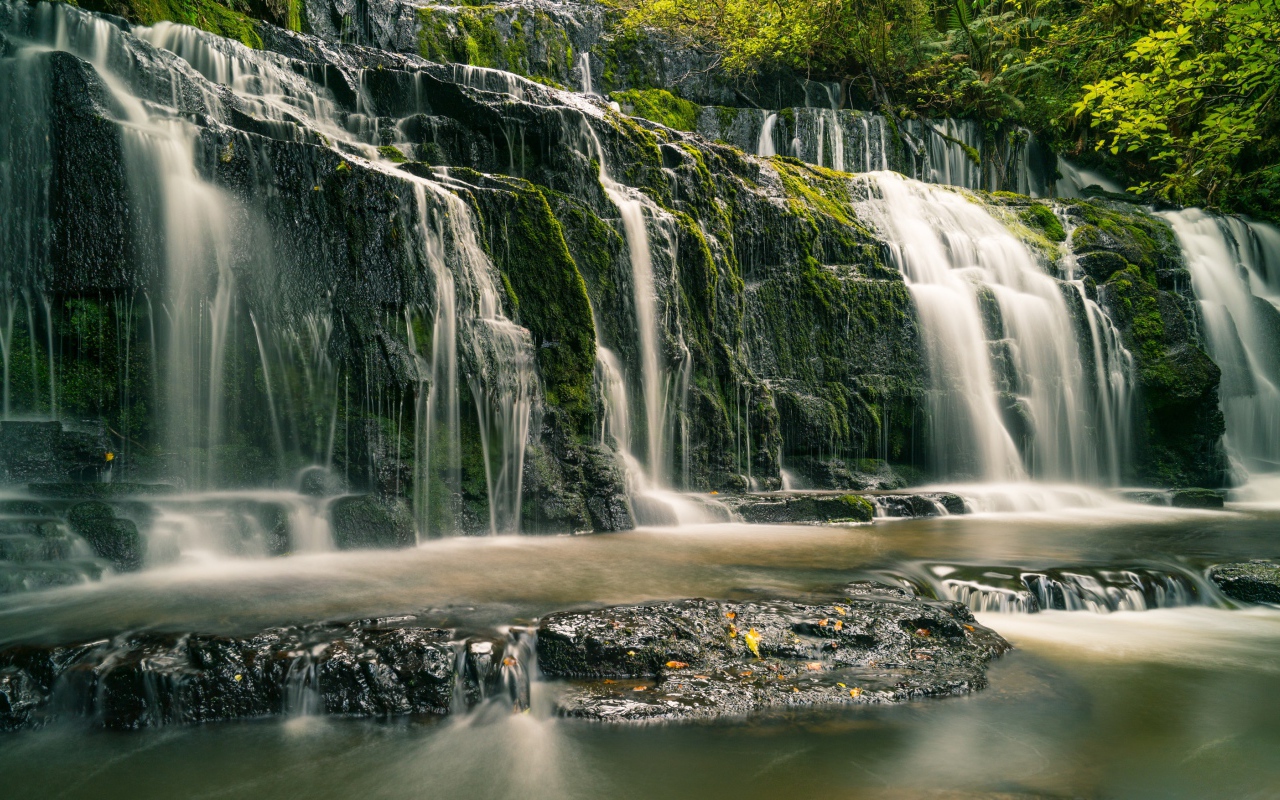 Водопад в лесу стекает по покрытым мхом камням 