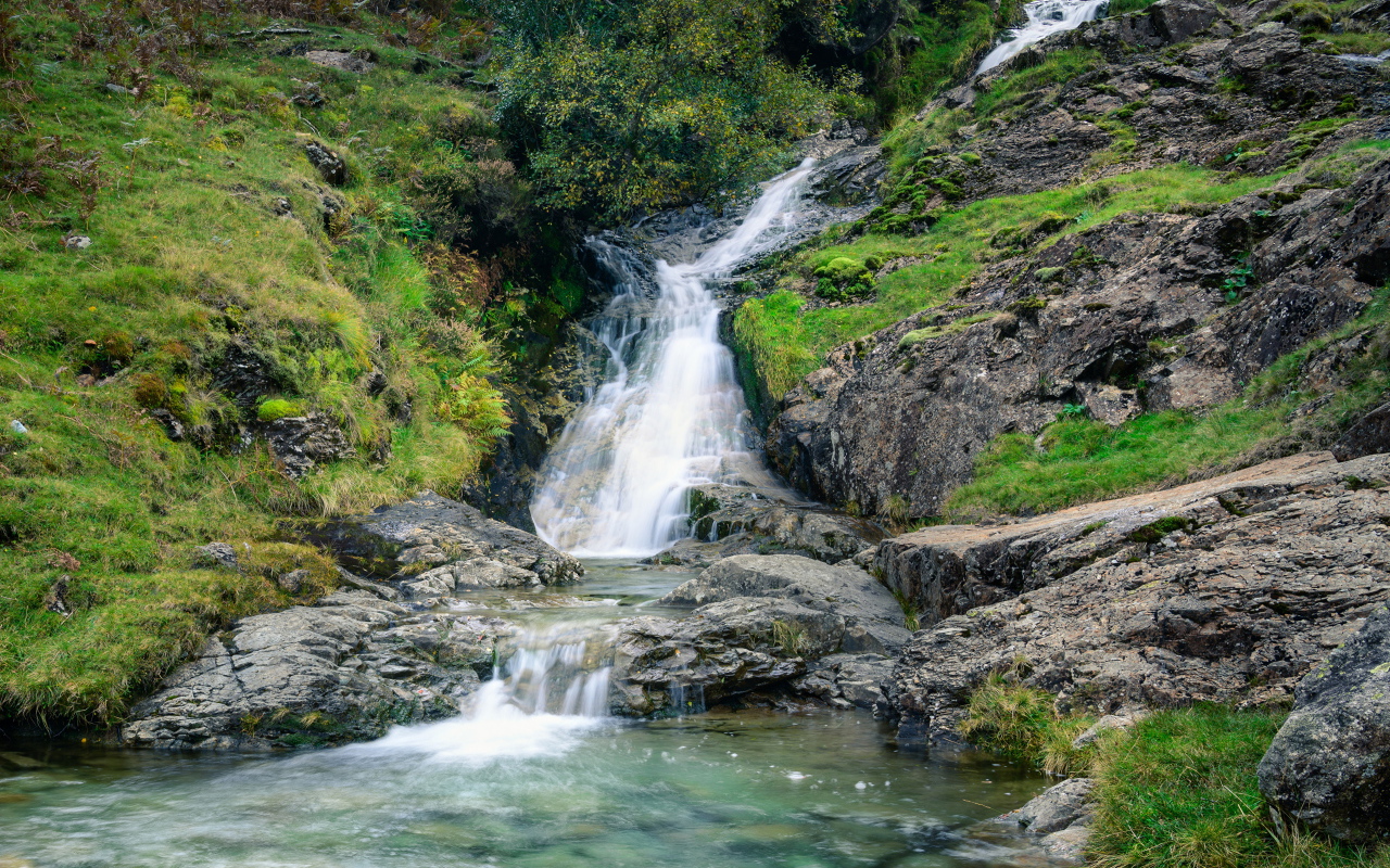 Горный ручей стекает по камням в реку 