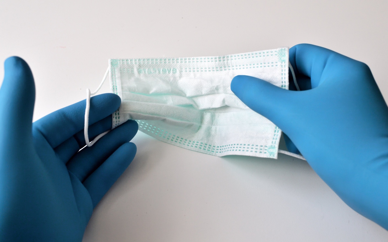 Руки в медицинских перчатках держат маску 