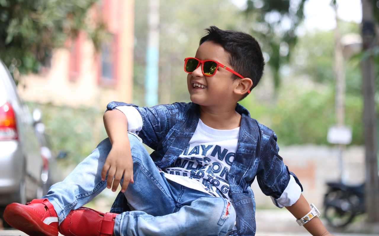 Маленький модный мальчик сидит на асфальте