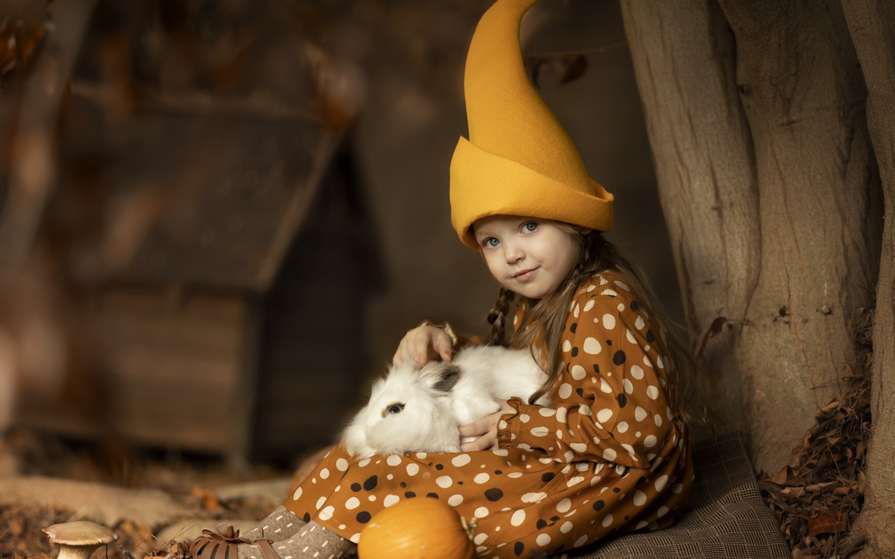 Маленькая смешная девочка в колпаке с кроликом