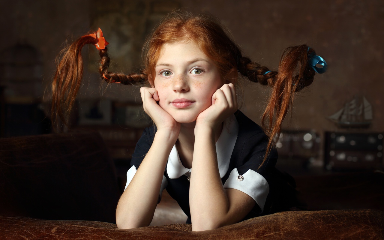 Маленькая смешная девочка с косами в школьной форме 