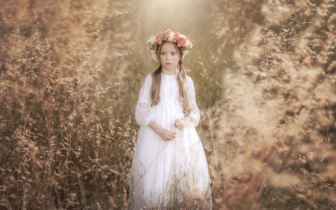 Маленькая девочка в белом платье с венком на голове 