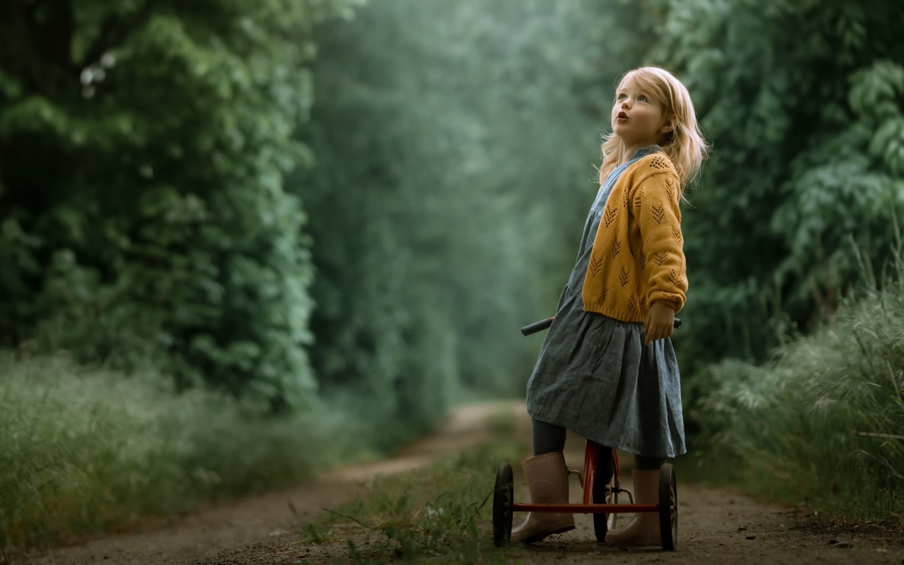 Маленькая девочка на трехколесном велосипеде 