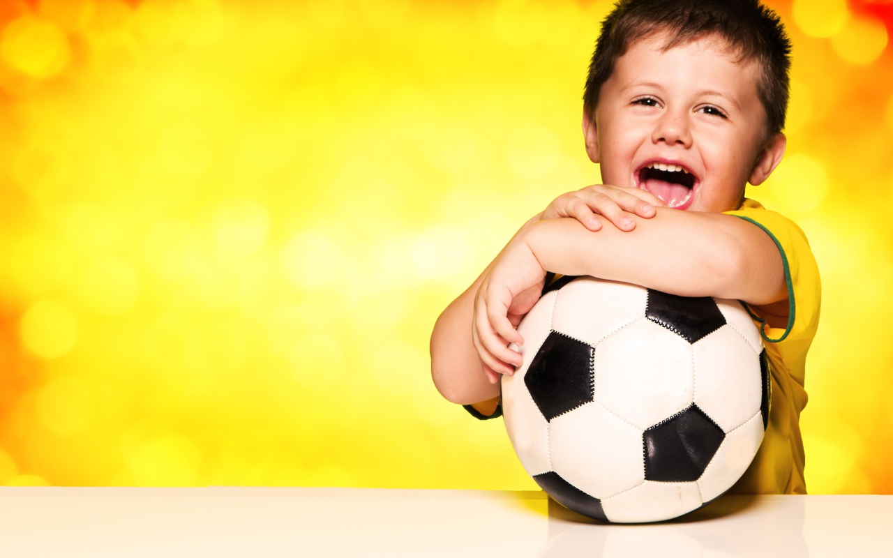 Маленький довольный мальчик с футбольным мячом