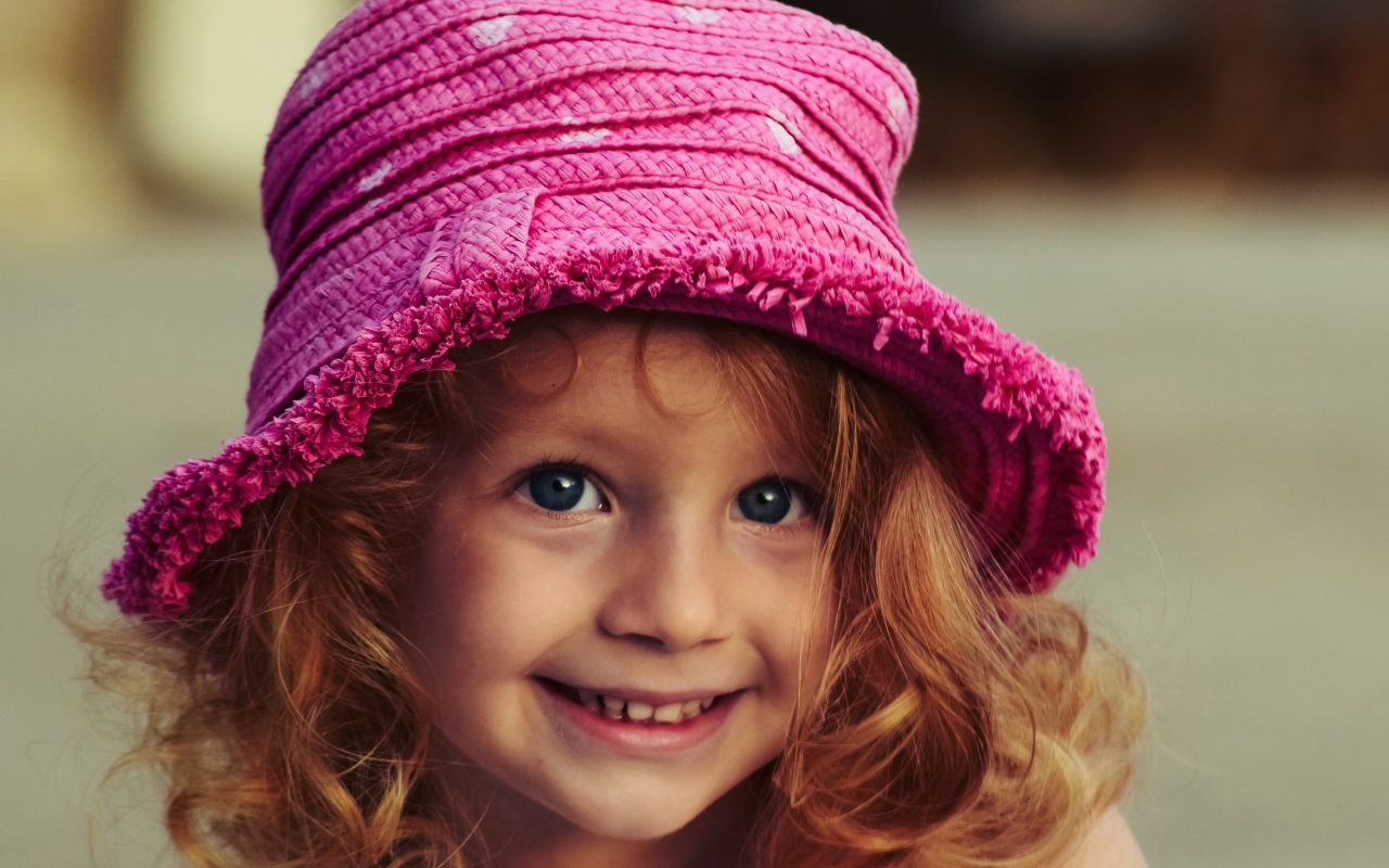 Маленькая улыбающаяся девочка в розовой шляпе