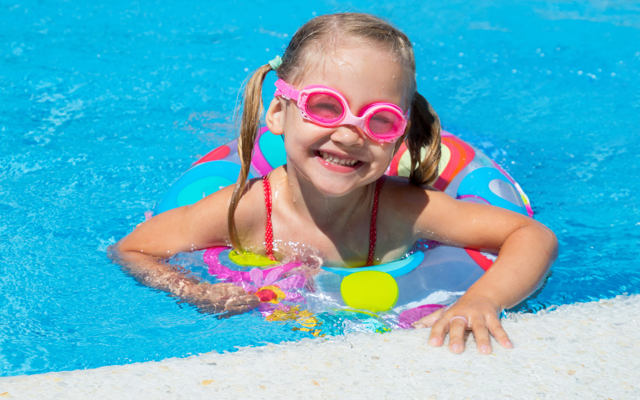 Улыбающаяся девочка с кругом в бассейне 