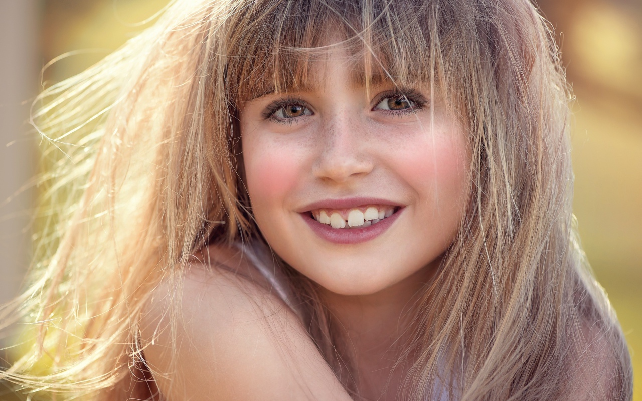 Улыбающаяся девочка с веснушками на лице 