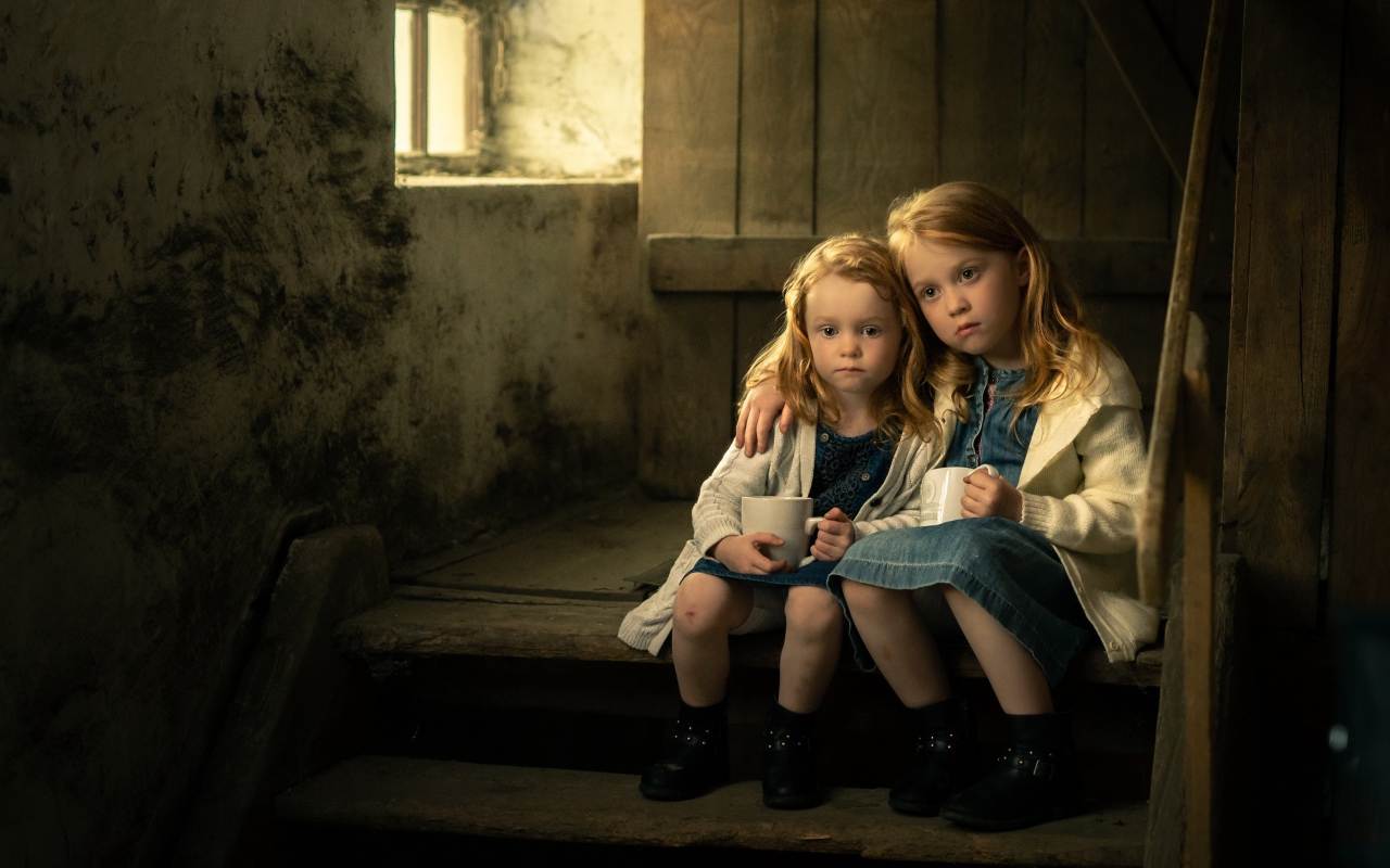 Две маленькие сестры пьют какао на ступеньках дома