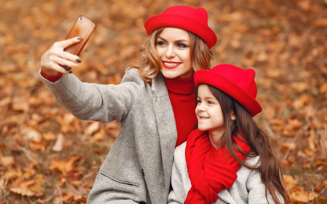 Женщина с маленькой девочкой делают селфи в лесу 