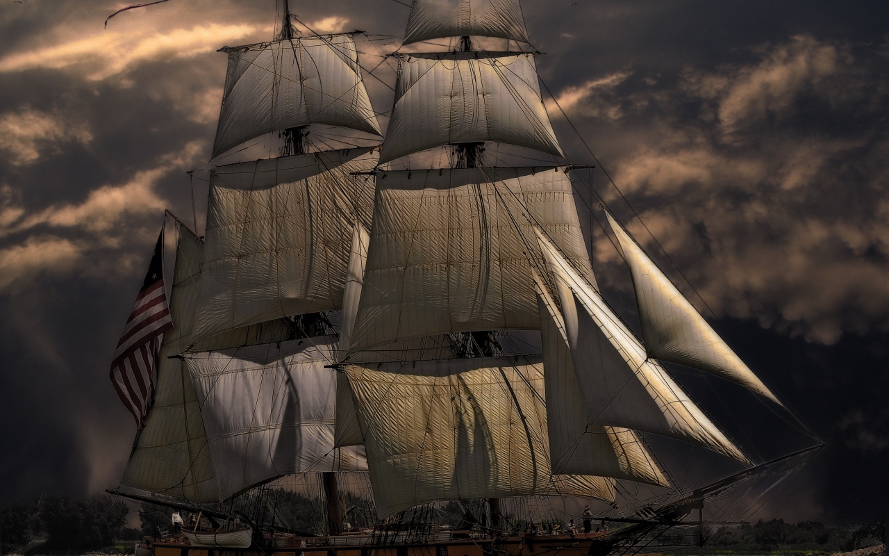 Больше судно с белыми парусами на фоне неба в сумерках 