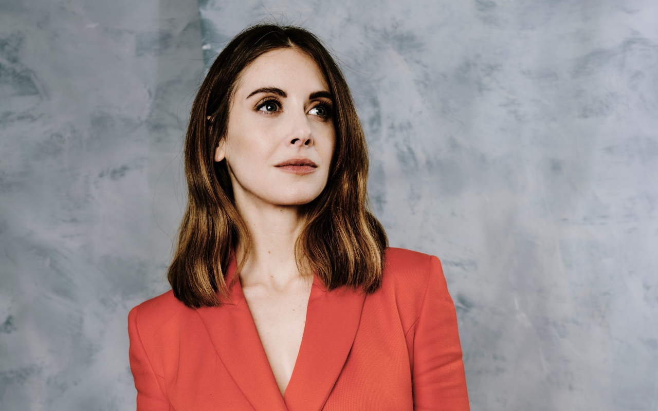 Актриса Элисон Бри в красном пиджаке на сером фоне