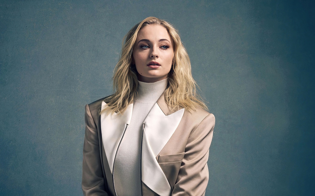 Актриса Софи Тёрнер в бежевом костюме на сером фоне