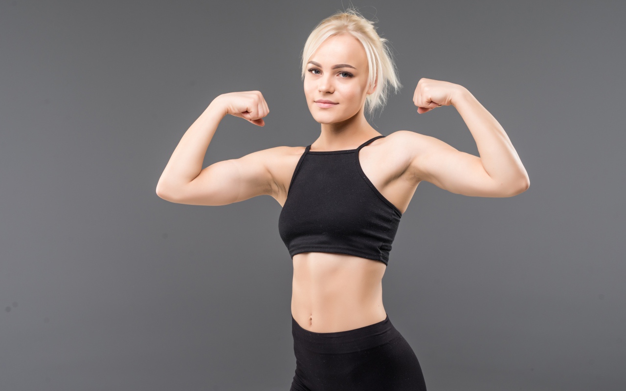 Красивая стройная спортивная девушка показывает мускулы