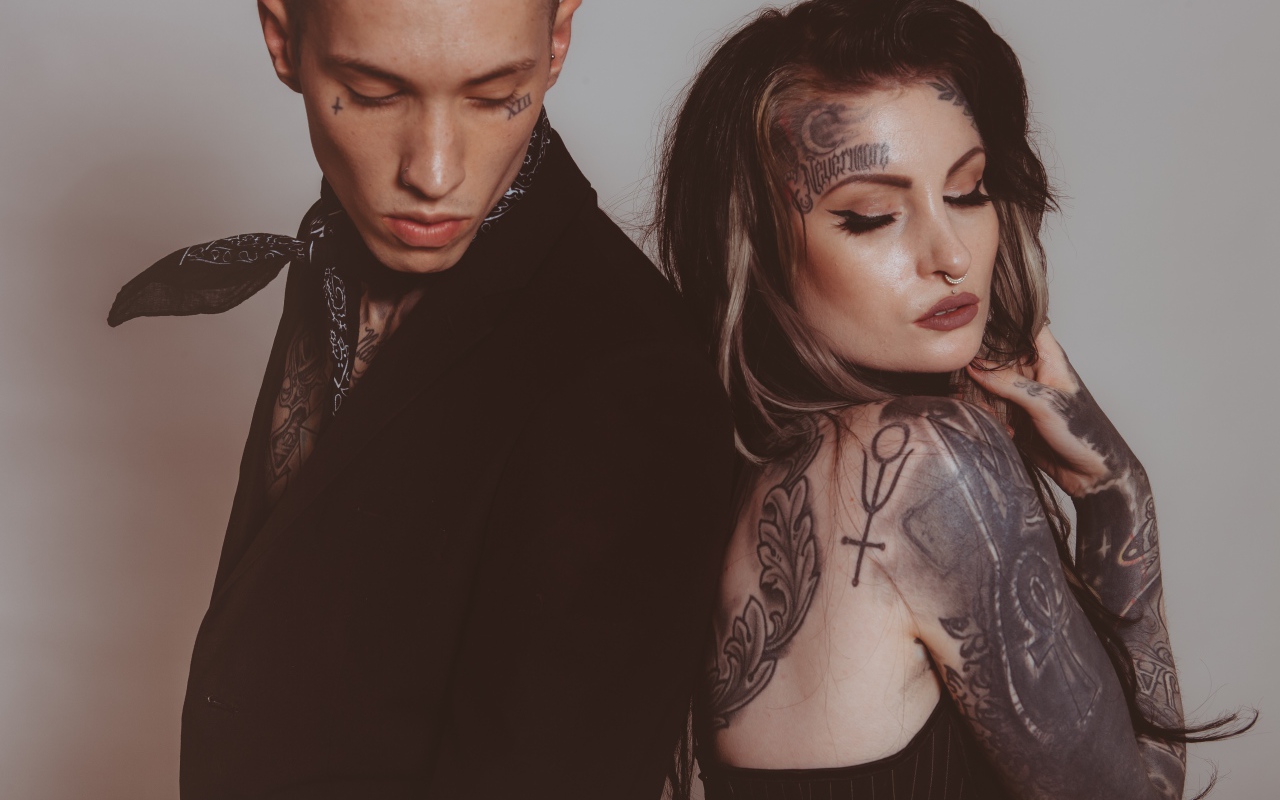 Девушка и парень с татуировками на теле на сером фоне