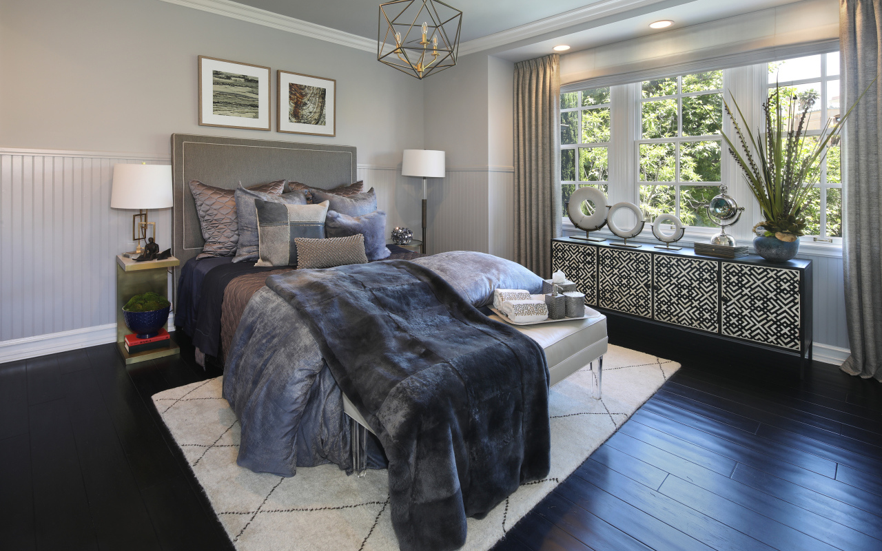 Большая кровать с мягким серым покрывалом в спальне 