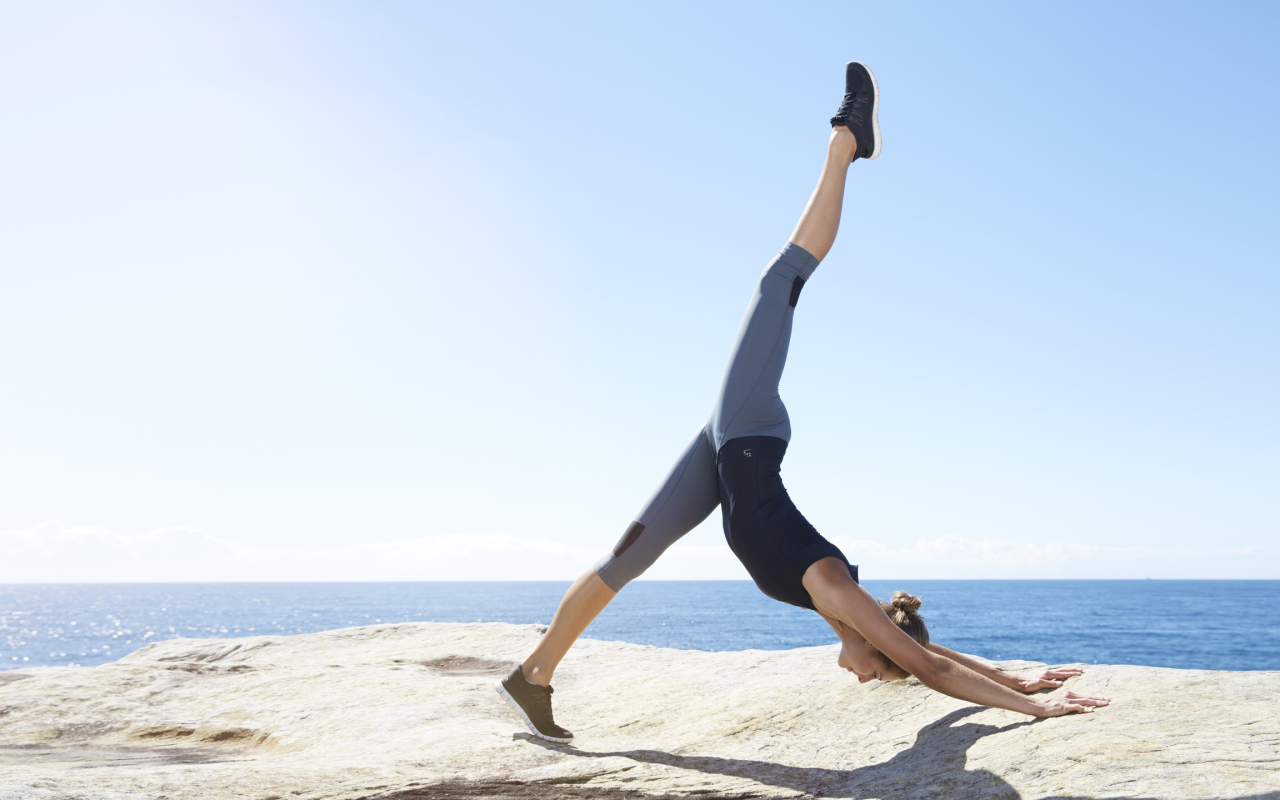 Спортивная девушка делает упражнения на берегу моря 