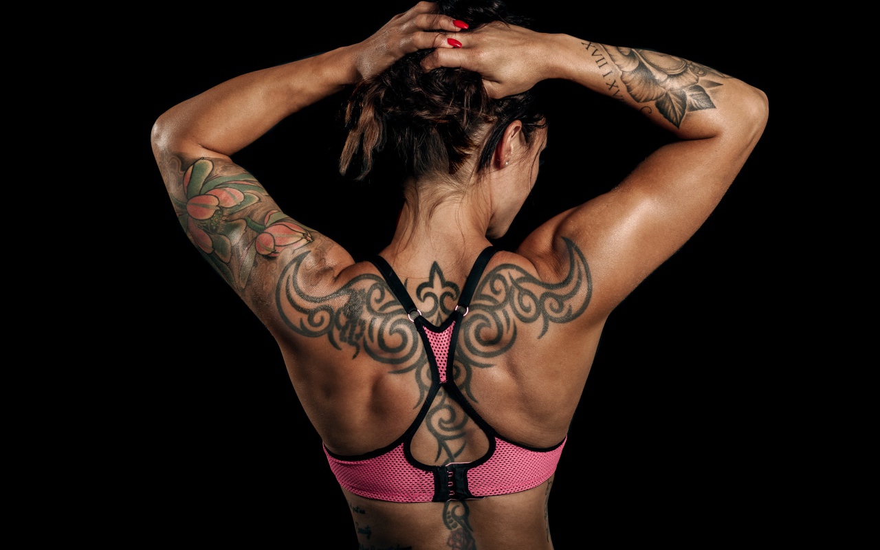 Tattoos on the body of a sports girl on a black background