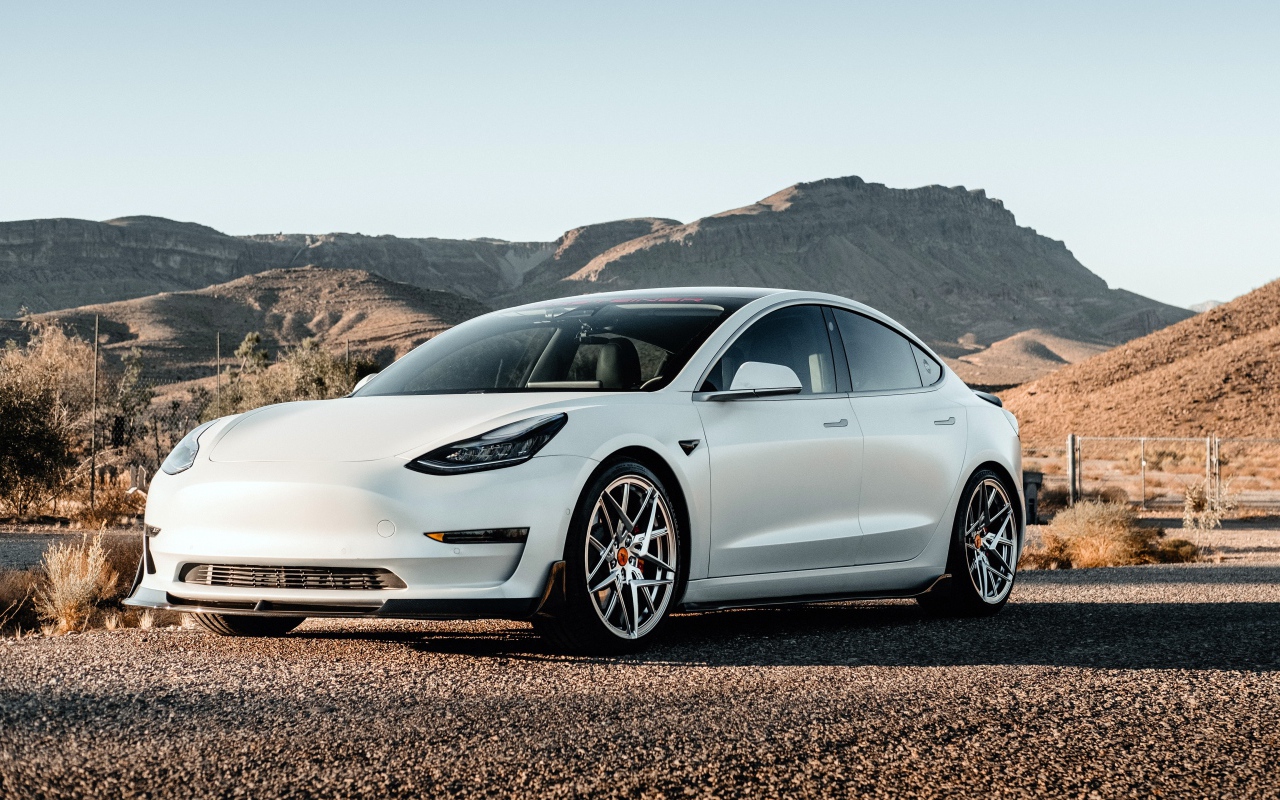Белый автомобиль Tesla Model 3 Volta 2019 года на фоне гор 