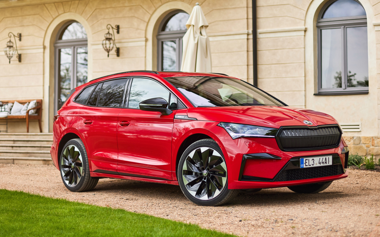 Красный автомобиль Skoda Enyaq Sportline IV 2021 года у стены