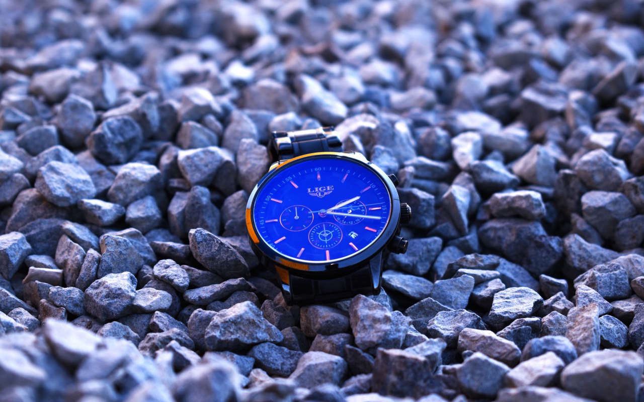 Голубые наручные часы лежат на камнях