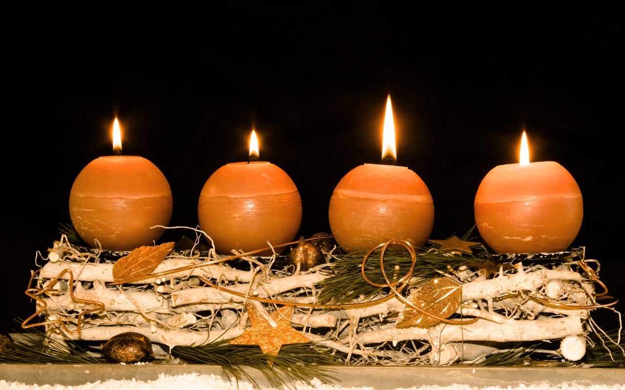 Четыре круглые зажженные свечи на черном фоне