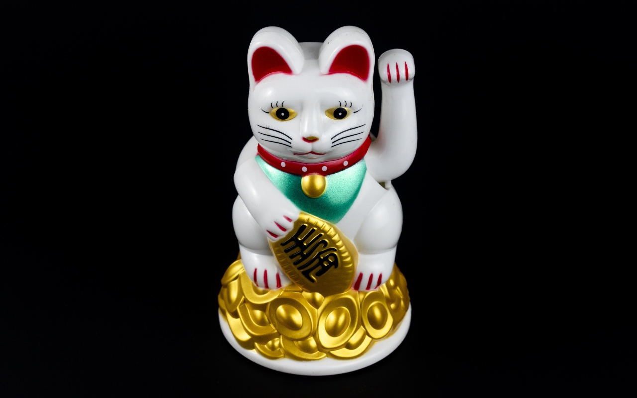 Японская фигурка манэки-нэко кошка на черном фоне