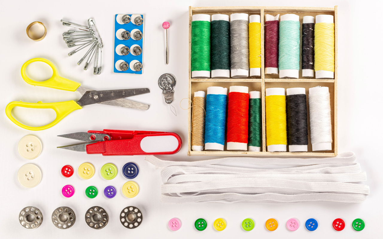 Разноцветые нитки и предметы для шитья на белом фоне 