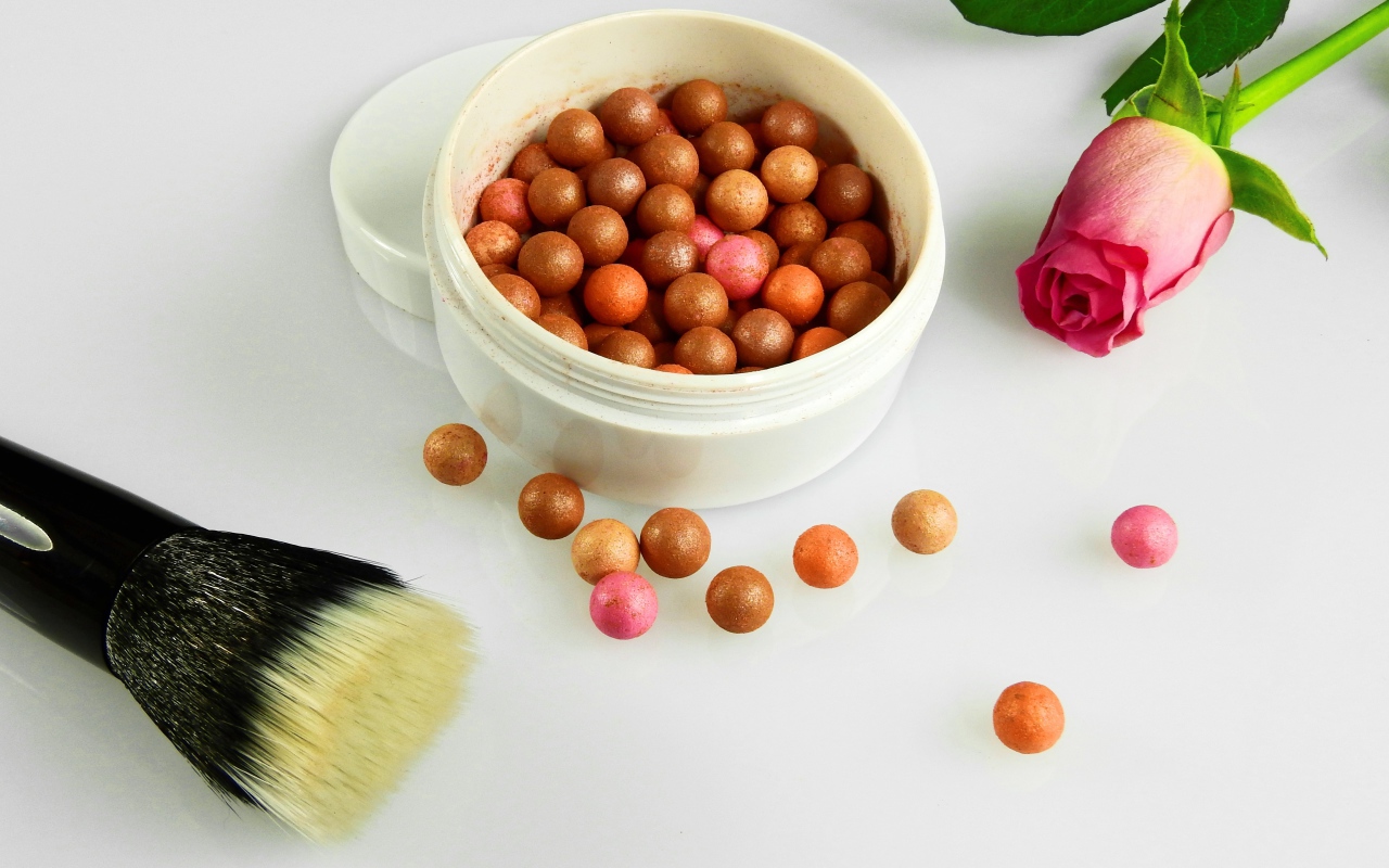 Шариковая пудра на белом фоне с кистью и розой