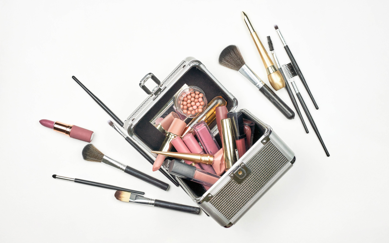 Набор косметики в чемодане на белом фоне