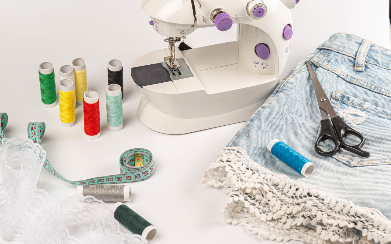 Швейная машинка,юбка и нитки на белом фоне 