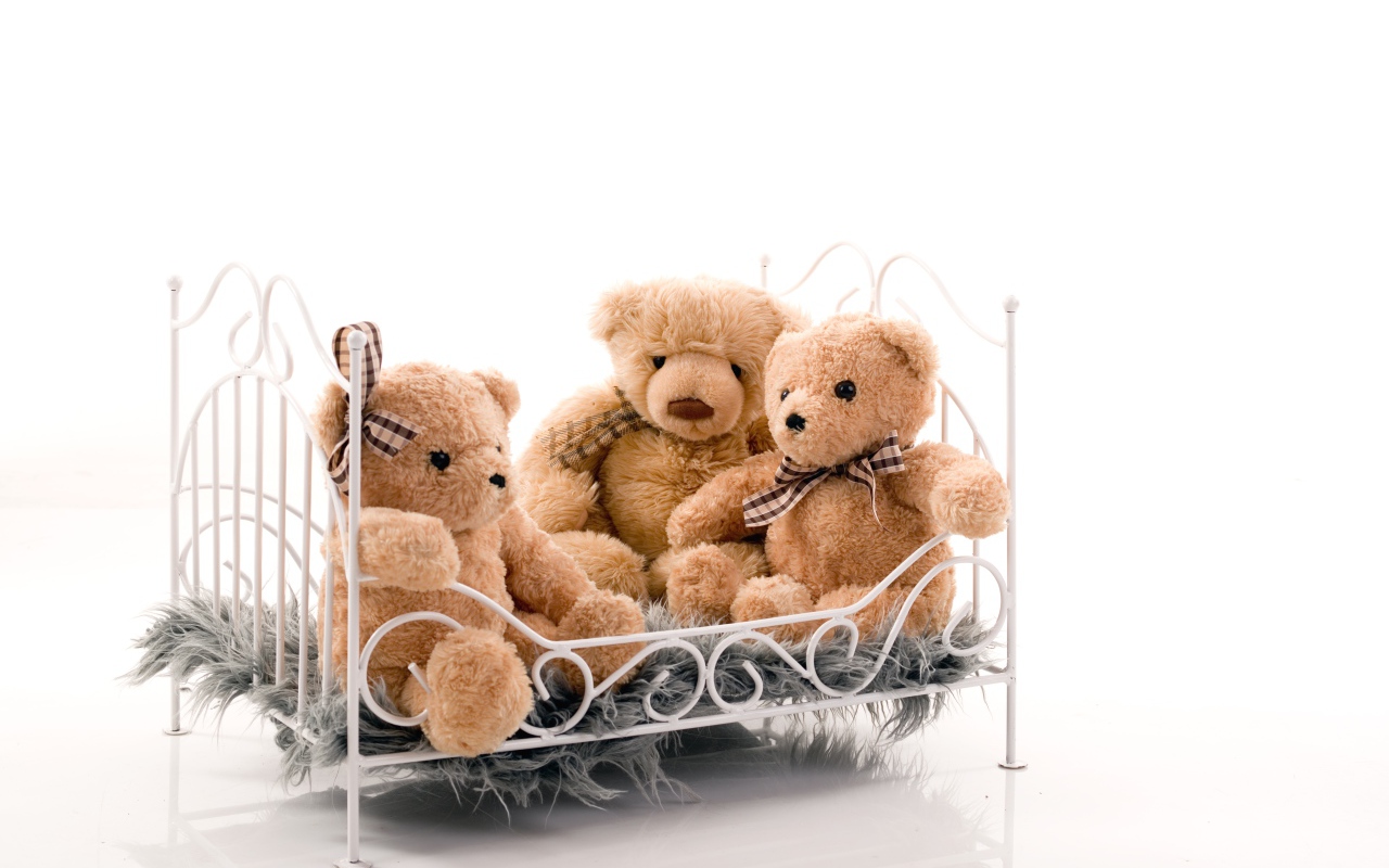 Три игрушечных медведя на кровати на белом фоне