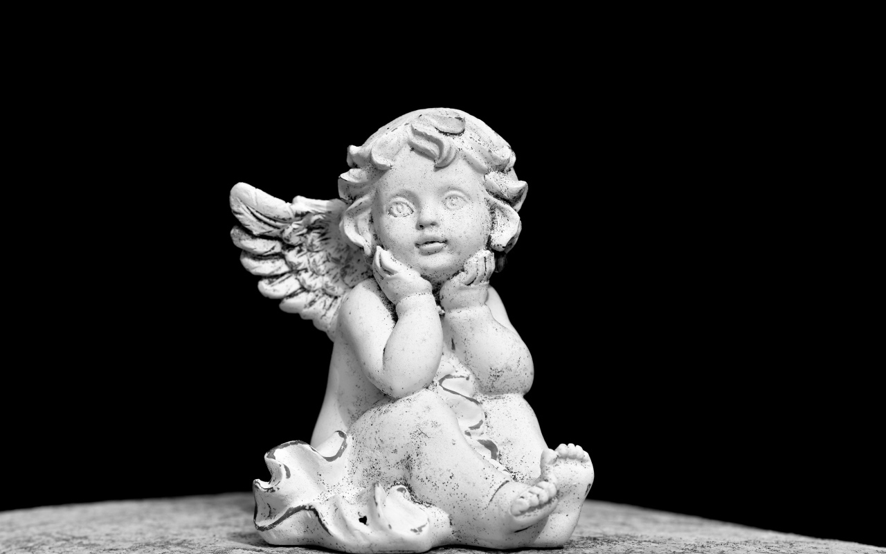 Белая статуэтка ангел на черном фоне