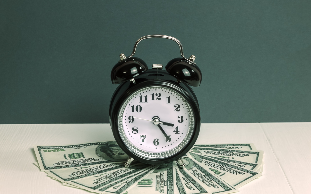 Черный будильник и доллары на столе