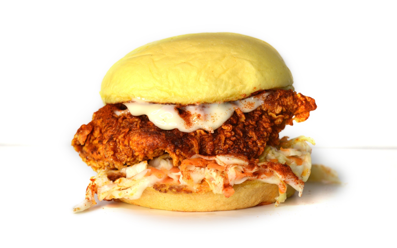 Большой куриный бургер с соусом на белом фоне